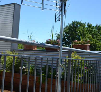 Installation d'une antenne TV HD multi-directionnelle sur la rampe d'un balcon